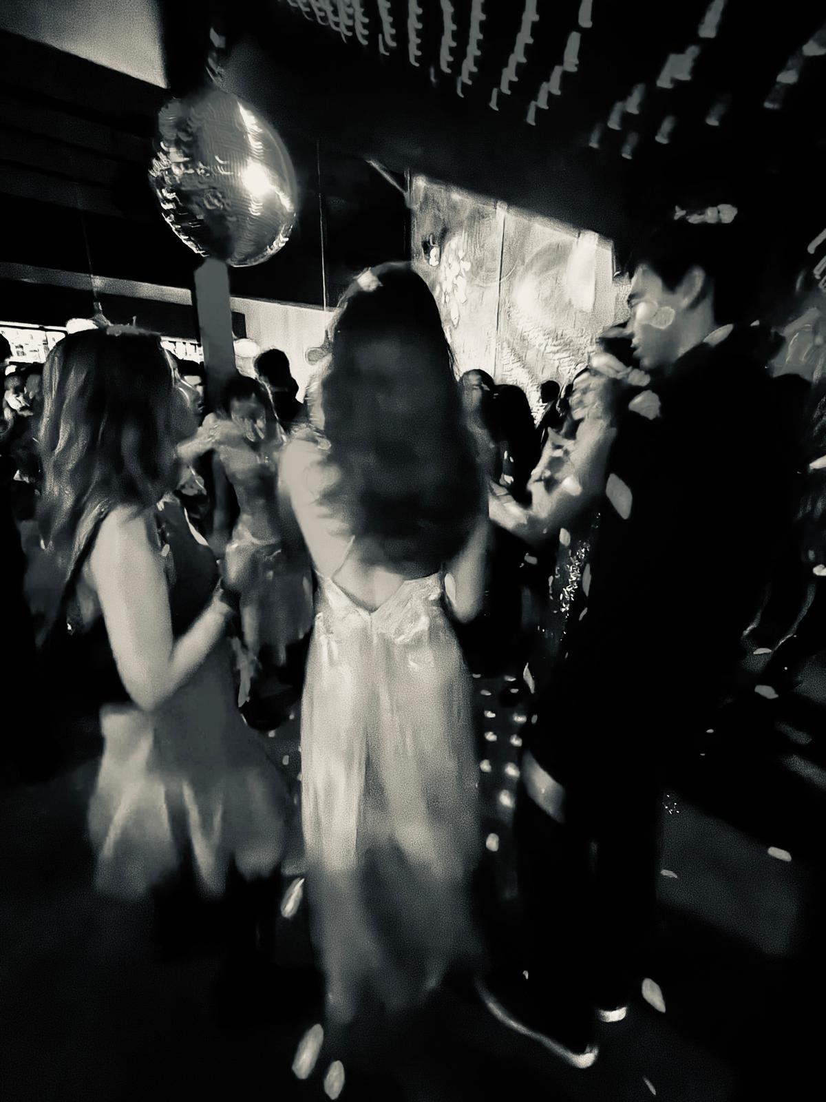 Atmospheric black and white photograph of a private party with disco ball and dancers