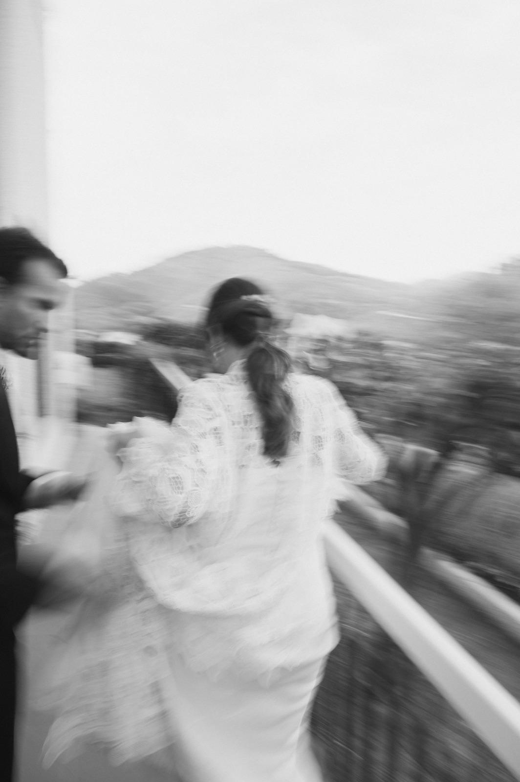 Artistically blurred black and white photograph of a bride in lace dress in motion